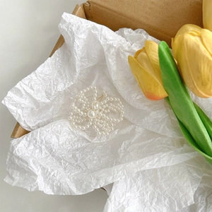 Detail view of a white pearl butterfly accessory inside a kraft gift box with tulips