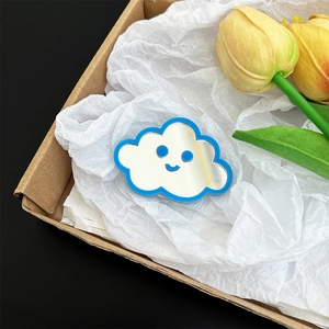 Detailed close-up of a cute cloud-shaped mirror phone grip with a blue smiley face