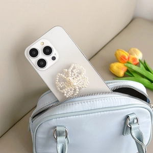 Detail of a pearl woven butterfly phone socket grip mounted on a white smartphone