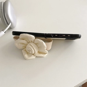 Macro shot of 3D cream camellia leather flower and wide wrist strap on black phone case