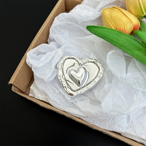 Detailed close-up of a silver metallic heart-shaped phone grip stand in a gift box