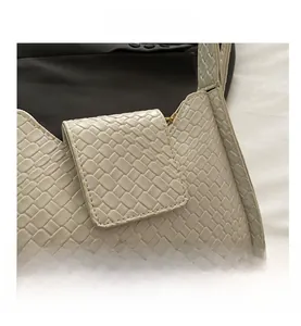 Détail du sac sous l'aisselle beige présentant une texture gaufrée tissée et un rabat