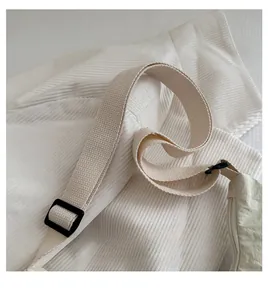 Gros plan sur la bandoulière tissée large et la boucle réglable noire du sac à bandoulière
