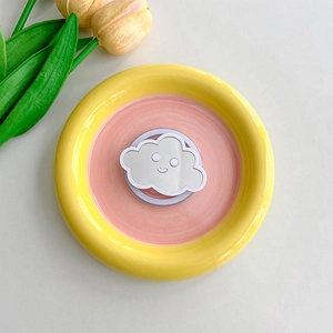 Cloud-shaped collapsible phone grip and makeup mirror with a smile icon in a ceramic tray
