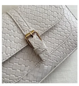 Close-up of white woven leather texture with elegant golden buckle detail on the bag