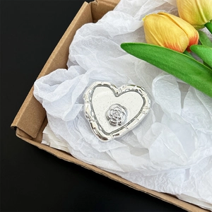 Detailed macro shot of a silver heart-shaped phone grip with rose motif in gift box