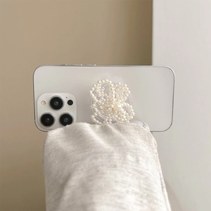 Detail of white pearl flower collapsible phone socket on white smartphone with hand hold