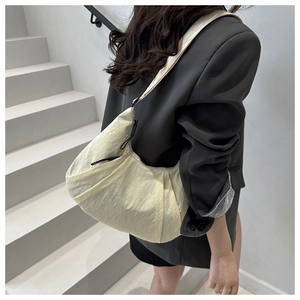 Detail of light yellow pleated crescent bag with black drawstring and wide woven shoulder strap