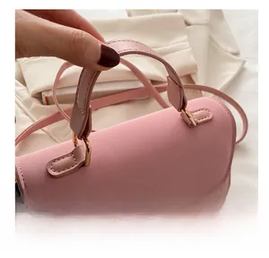 Detail of pink matte handbag showing slim handle and elegant gold-tone hardware