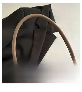 Detail van kaki lederen schoudertas met dikke riem op een zwarte blazer achtergrond