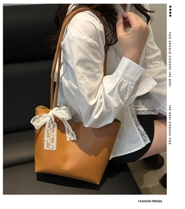 Detail der braunen Shopper-Tasche aus Kunstleder mit weißer Spitzenschleife