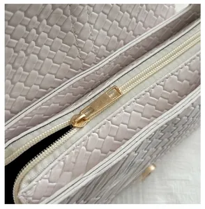 Detailed macro view of woven leather texture and smooth light gold zipper closure