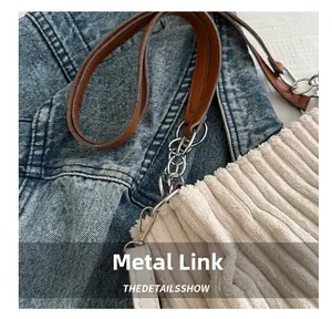 Detailed macro view of silver metal chain links on a corduroy shoulder bag strap