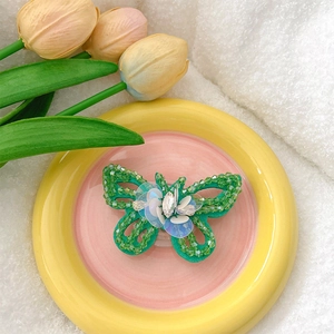 Detail of green butterfly phone stand with sequins and beads on a decorative plate