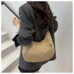 Détail du sac croissant kaki en tissu nylon plissé porté par un mannequin
