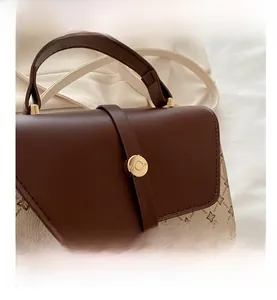 Detailed close-up of textured monogram fabric and brown leather flap with gold buckle