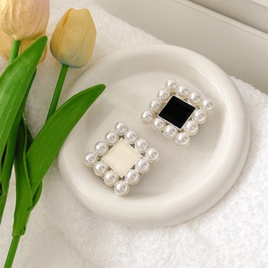 Detail of square gold phone grip with pearl border and black/white enamel inlay