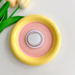 Detail of a rhinestone-encrusted round mirror phone grip on a ceramic plate with tulips
