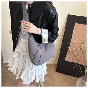 Détail du sac bandoulière croissant gris-violet en nylon plissé porté par un mannequin