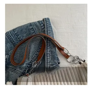 Detail of corduroy tote bag with brown leather strap and silver chain link accents