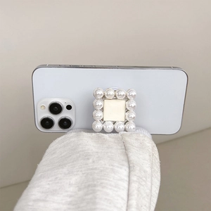 Detail of square pearl-embellished pop-up phone socket on a white smartphone back
