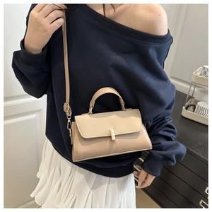 Detail of beige leather crossbody bag with golden metal bar lock and slim shoulder strap