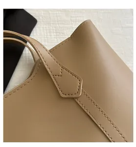 Detail of brown leather tote bag showing refined stitching and strap attachment point