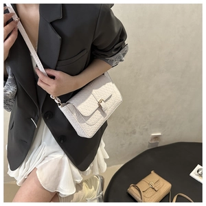 Détail du sac carré en cuir tressé avec boucle dorée, texture et bandoulière longue