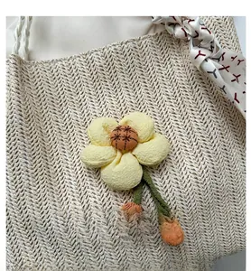Détail du sac cabas tissé avec fleur en tissu 3D et foulard en soie sur la poignée