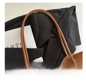 Detalle del asa del bolso de cuero marrón con herrajes de bronce y lazo de encaje blanco