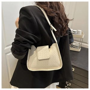 Détails de la texture tissée et du rabat sur ce sac à bandoulière minimaliste crème