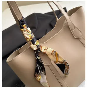 Close-up of beige tote bag handle with elegant geometric print silk scarf decoration
