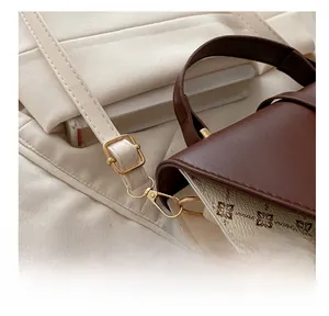 Close-up of golden metal buckle and brown leather strap on vintage floral crossbody bag