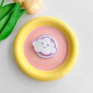 Macro detail of cloud-shaped phone grip with yellow and pink pastel decorative base