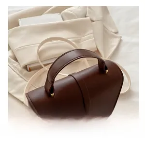 Detail view of a vintage dark brown leather crossbody bag with cream shoulder strap