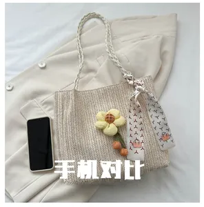 Détail du sac seau en paille tissée avec breloque tournesol et foulard décoratif