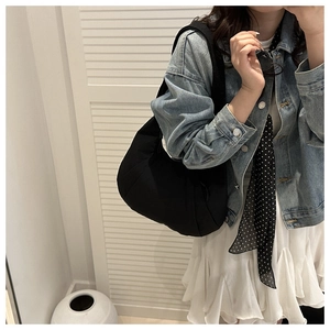 Sac hobo noir minimaliste en nylon porté sur l'épaule avec une finition mate