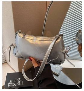 Detail einer silbernen Metallic-Tasche mit Nietenakzenten und Schleifenverzierung