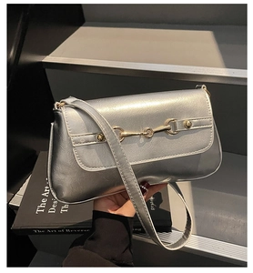 Detail of silver metallic baguette bag with golden horsebit buckle and glossy finish