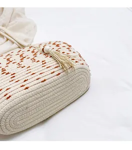 Detail of woven straw tote bag with brown spots, cotton tassels and wooden beads decor