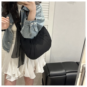Detail view of the black pleated dumpling bag showing waterproof nylon texture and strap