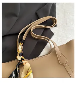 Detail of khaki leather handbag handle wrapped with a decorative patterned silk scarf