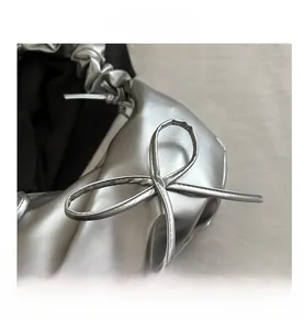 Close-up of silver metallic cloud bag featuring ruffled drawstring and bow detail