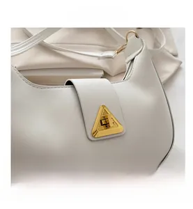 Dettaglio macro della borsa minimalista in pelle bianca con fibbia dorata a triangolo