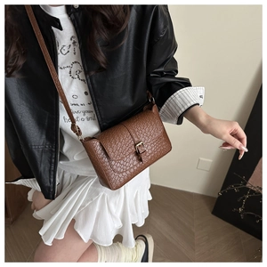 Close-up of brown crocodile pattern embossed shoulder bag with gold pin buckle detail
