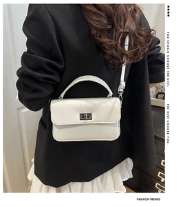 Détail du petit sac carré en cuir blanc avec fermoir argenté porté par un mannequin