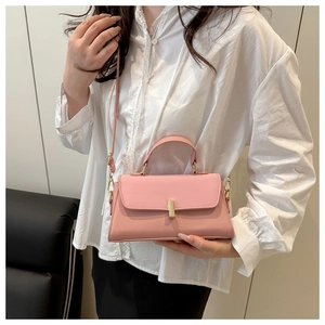 Detail of the pink leather handbag showing a round handle and gold metal twist lock