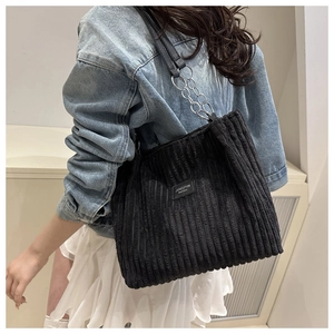 Detail of black corduroy tote bag showing metal chain strap and Jingpin leather label