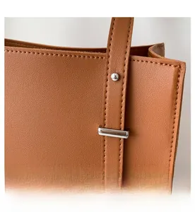 Close-up of brown PU leather texture with silver hardware and neat stitching details