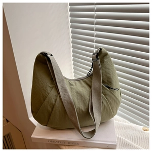 Détail du sac demi-lune en nylon vert olive avec des plis élégants et bandoulière réglable